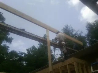 Carpenter setting a ridge beam over a new addition frame — Ice Dam Removal by Roofing Brothers in Coin
