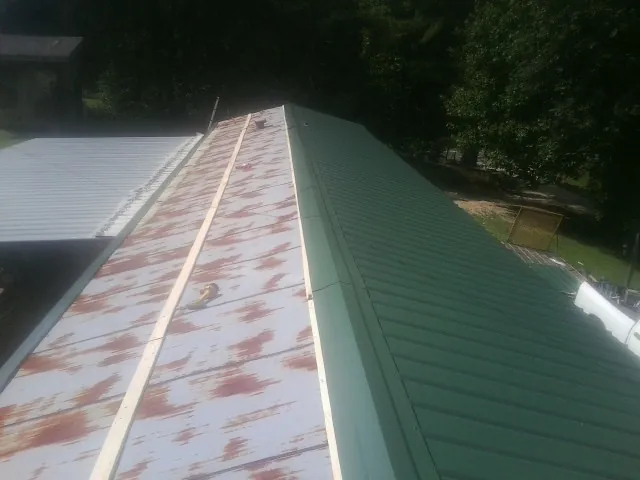 Old rusted panels beside newly installed green metal roofing — Wind Damage Roof Repair by Roofing Brothers in Coin