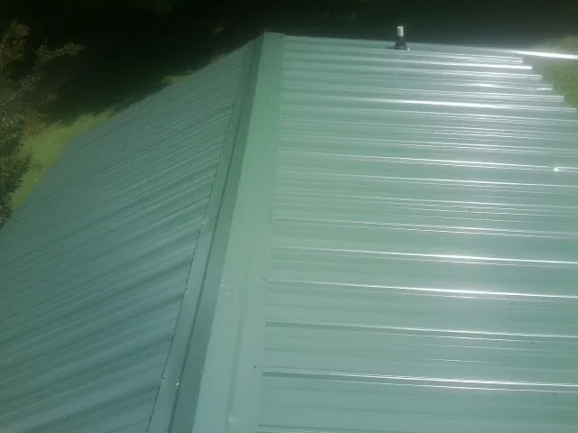 New green metal panels meeting at the ridge of a roof — Flat Roof Repair work by our crew in Coin
