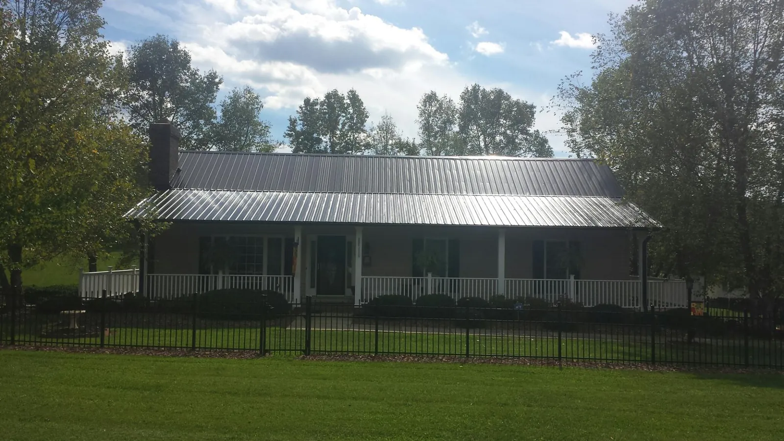 Gray metal roof on a brick ranch with a full width front porch — Gutter Guard Installation work by our crew in Coin