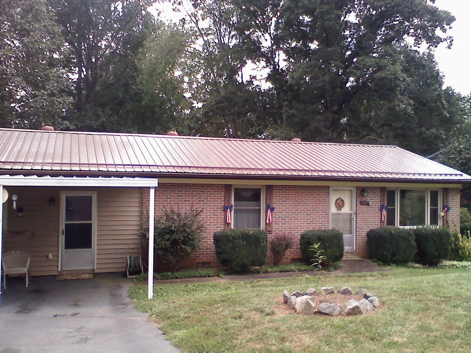 Bronze metal roof and carport on a brick ranch home — Roof Repair work by our crew in Coin