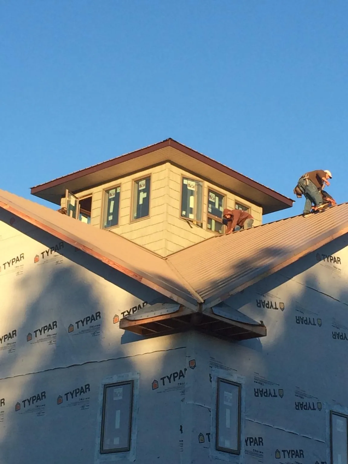 Roofers working around a rooftop cupola on a new metal roof at sunset — Roof Waterproofing in Coin by Roofing Brothers